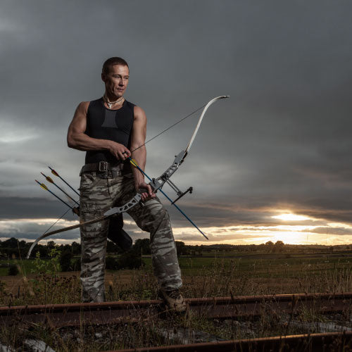 Archer holding a bow and arrow with background sunset